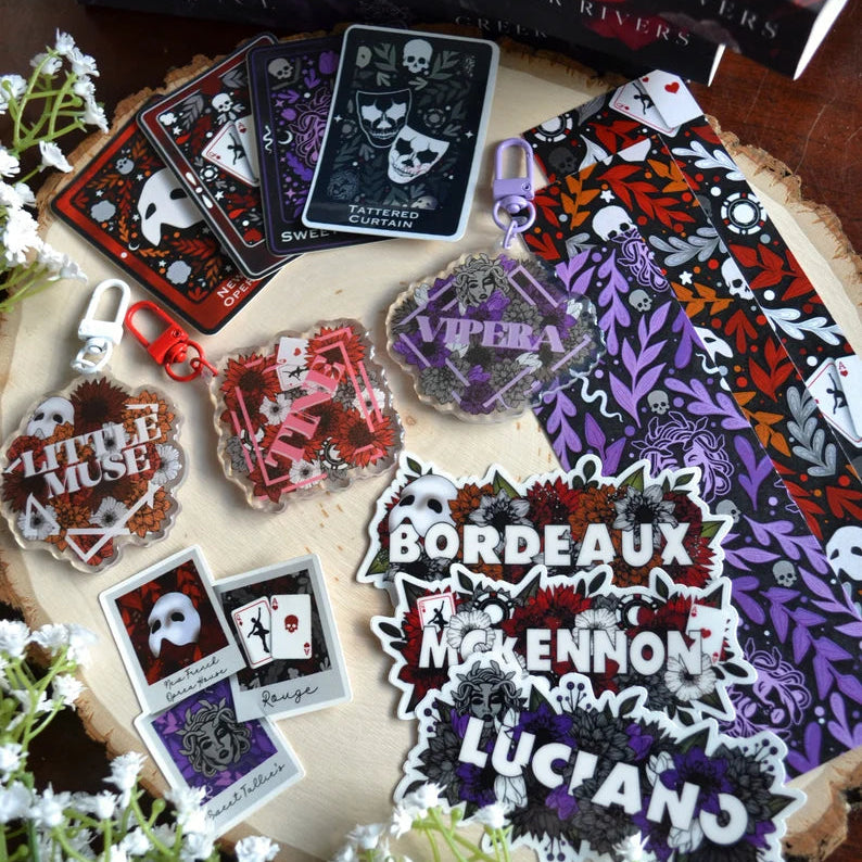 Collection of branded merchandise including cards, keychains, and stickers on a wooden surface with flowers.